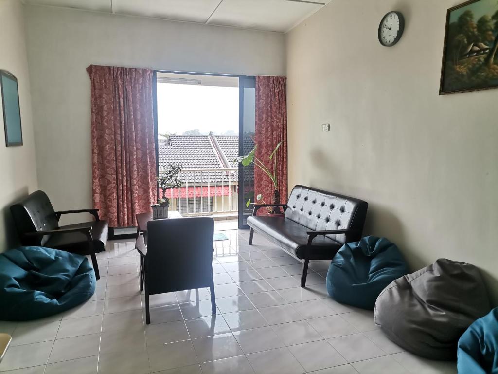 ein Wohnzimmer mit einem Sofa und Stühlen sowie einem großen Fenster in der Unterkunft EBH guesthouse in Malakka