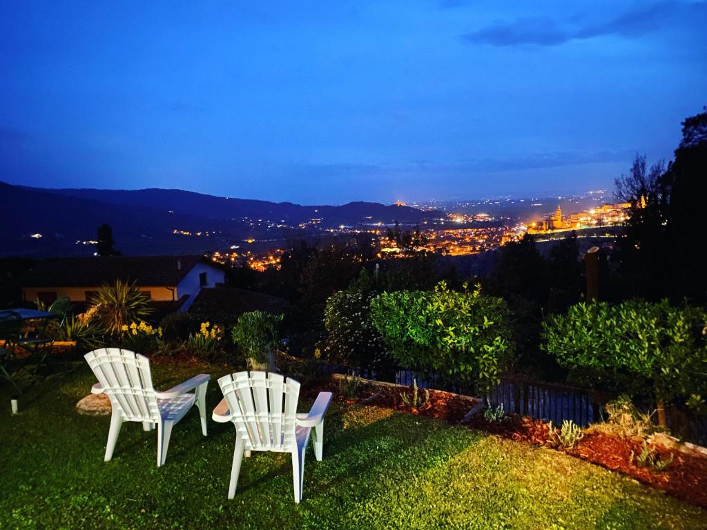 two white chairs sitting on a lawn at night at Panoramic View Village of Villa Luigina Cortona in Castiglion Fiorentino