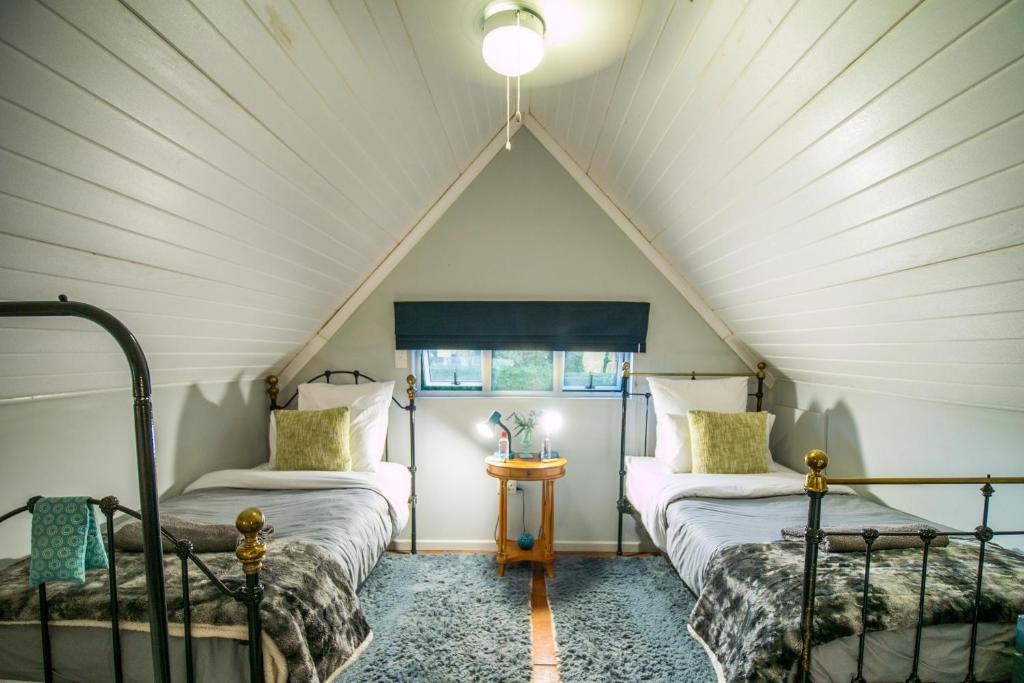 um quarto no sótão com 2 camas e uma janela em Glen Islay Cottage Himeville em Himeville