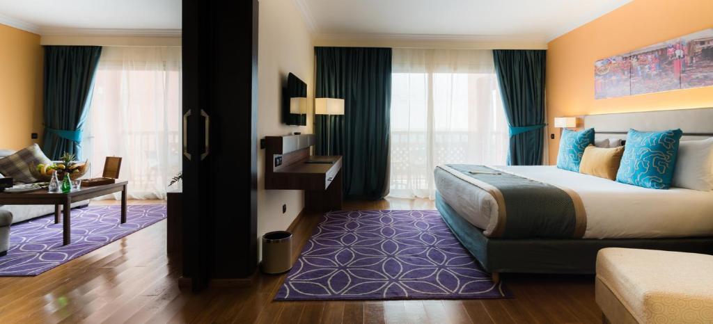 a hotel room with a large bed and a desk at Savoy Le Grand Hotel Marrakech in Marrakesh