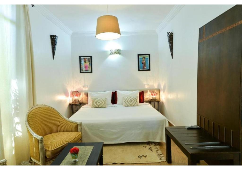 ein Schlafzimmer mit einem Bett, einem Stuhl und einem Tisch in der Unterkunft L'AUBERGE DE TENNIS MSC in Marrakesch