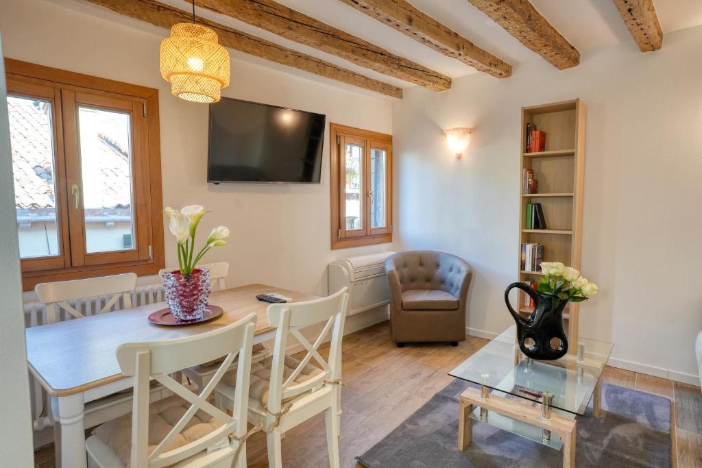 un soggiorno con tavolo da pranzo e TV di Ecco Suites Apartments a Venezia