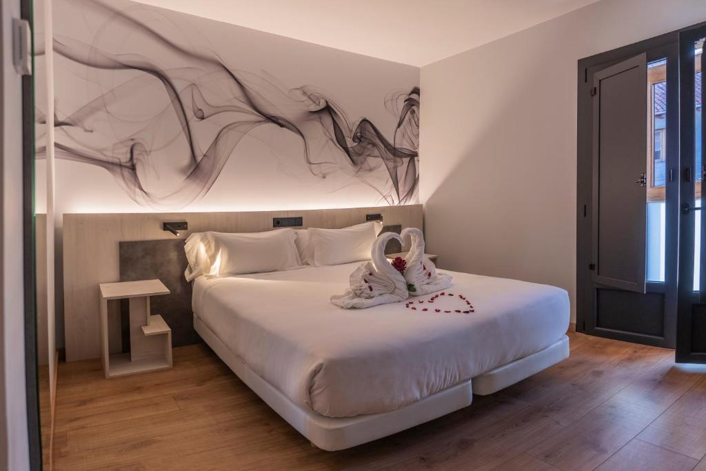 1 dormitorio con 1 cama con una pintura en la pared en Hotel NERU con Encanto en León