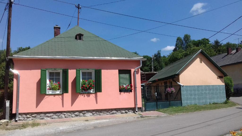 uma casa cor-de-rosa com caixas de flores nas janelas em Liána Vendégház em Szilvásvárad