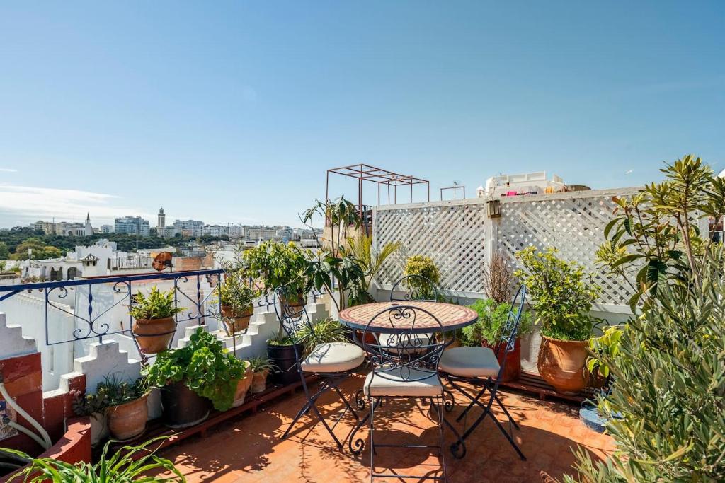 a balcony with a table and chairs and potted plants at DAR YAMNA Maison typique Kasbah de Tanger in Tangier