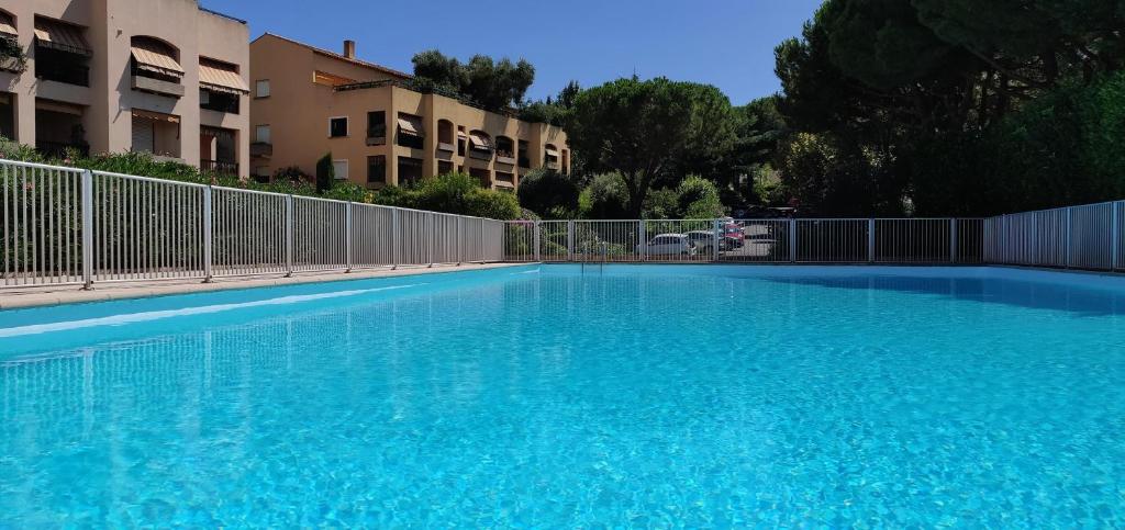 une grande piscine bleue en face de certains bâtiments dans l'établissement Appartement de charme wi-fi ,clim, garage jardin privés, piscine environnement arboré, à Cannes