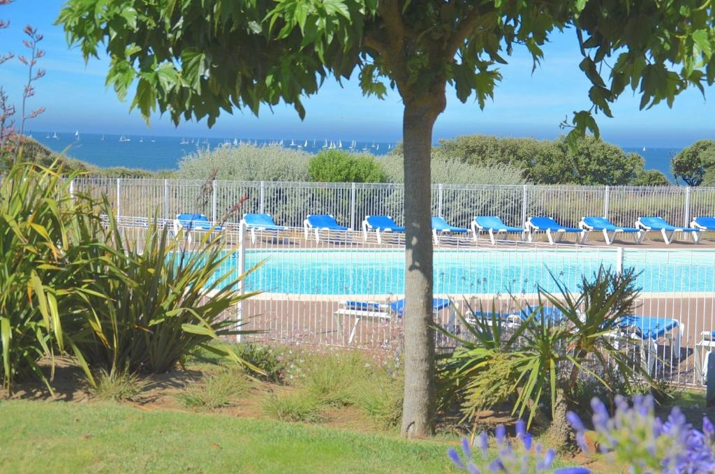 a swimming pool with chairs and the ocean in the background at Appartement 2 pièces dans résidence bord de mer aux Sables d'Olonne in Les Sables-d'Olonne