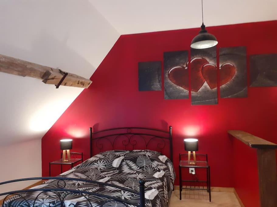 Verdelot的住宿－studio atypique et reposant，卧室的墙壁上设有红色的墙壁,墙上有两颗心