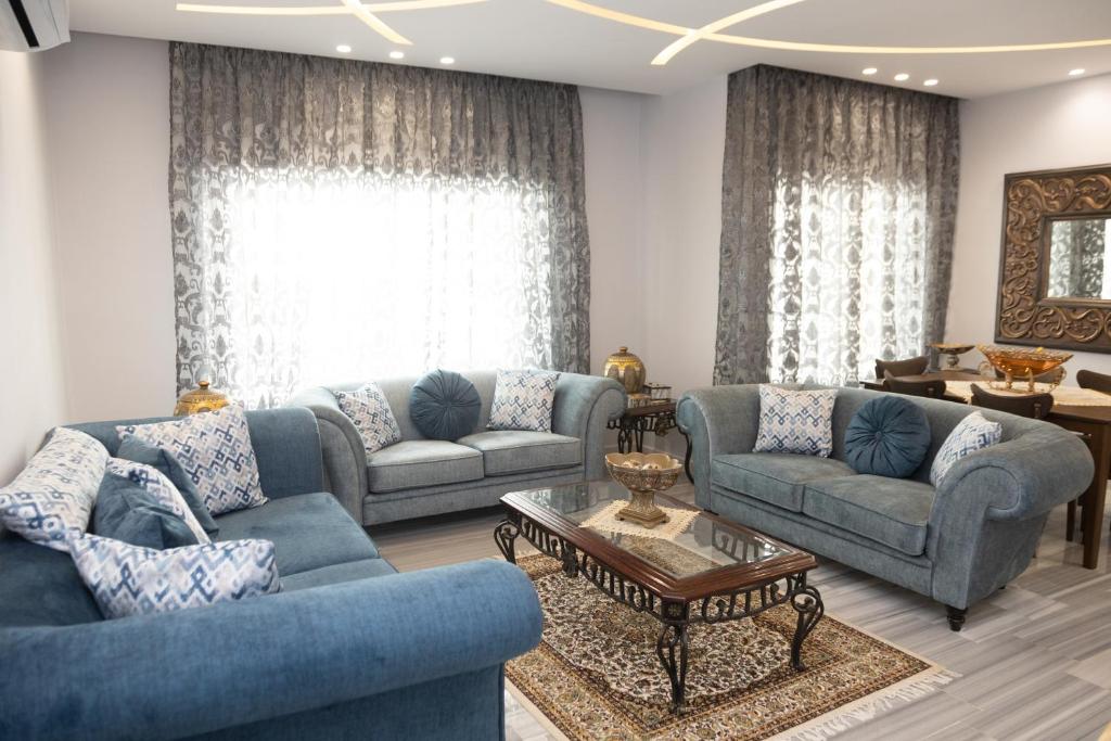 ein Wohnzimmer mit 2 blauen Sofas und einem Tisch in der Unterkunft Luxury 3BR Apartment, Der Ghbar 165m2 in Amman