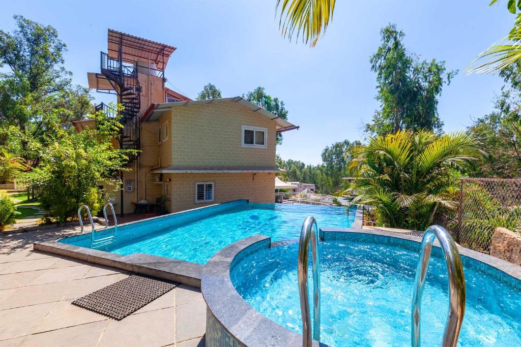 ein Swimmingpool vor einem Haus in der Unterkunft StayVista's Chimney Cottage with Sprawling Lawns, Picturesque Views, Plunge Pool, Jacuzzi, and Home Theatre in Panchgani