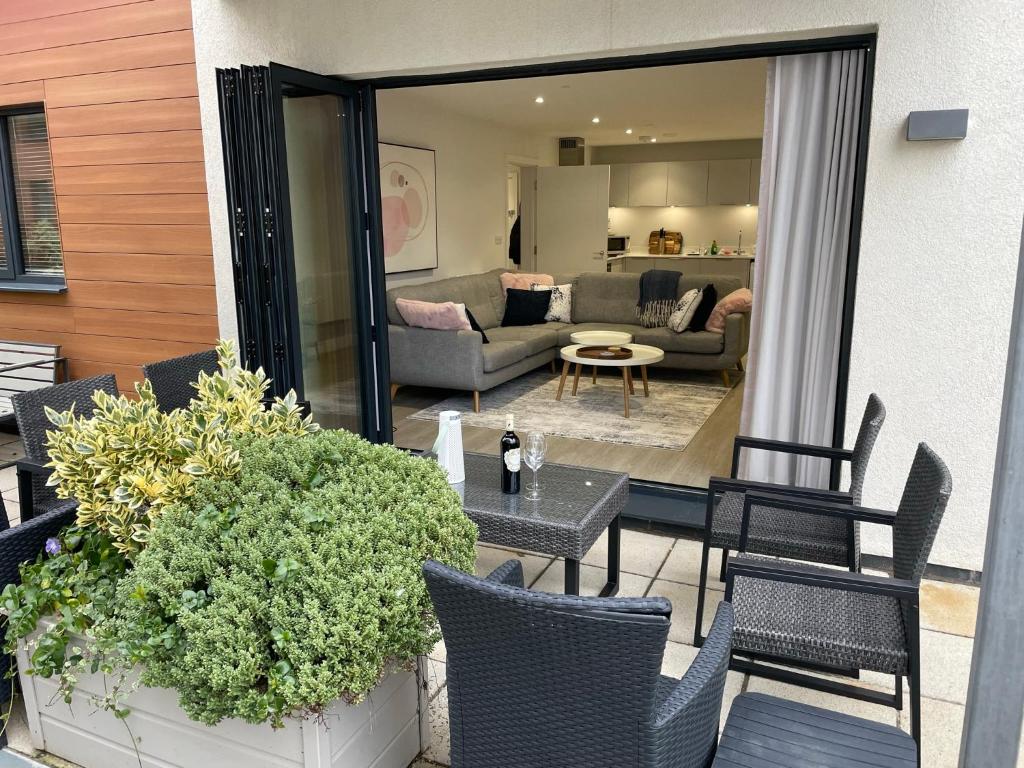 een patio met stoelen en tafels en een woonkamer bij 4 Putsborough - Luxury Apartment at Byron Woolacombe, only 4 minute walk to Woolacombe Beach! in Woolacombe