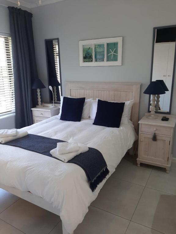 a bedroom with a large white bed with blue pillows at Croeso Guest House in Langebaan