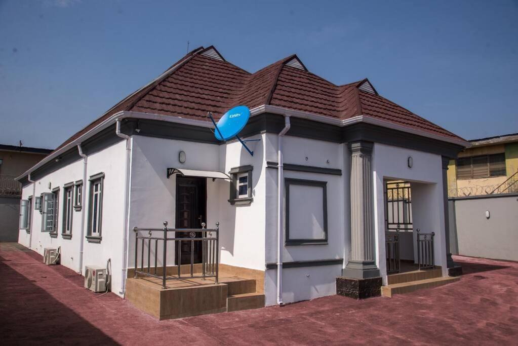 une petite maison blanche avec un toit marron dans l'établissement TFP Lodge, à Ibadan