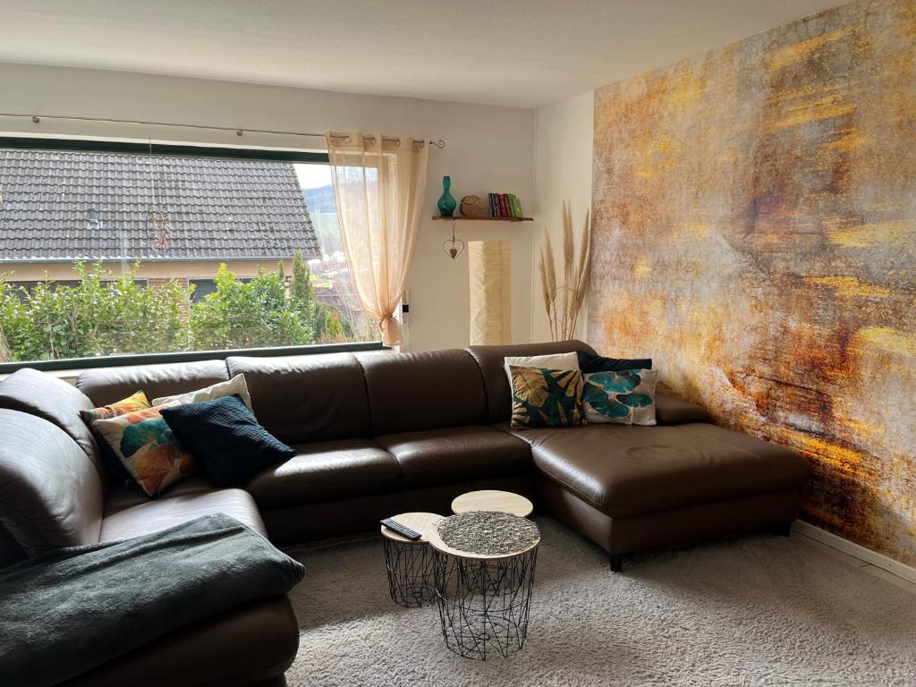 a living room with a leather couch and a large window at Spitzenbergblick in Reichensachsen