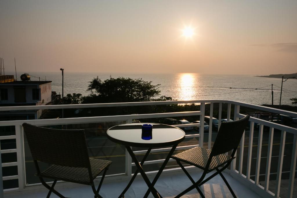 a table and chairs on a balcony with the ocean at 岸戀民宿 墾丁船帆石 in Eluan