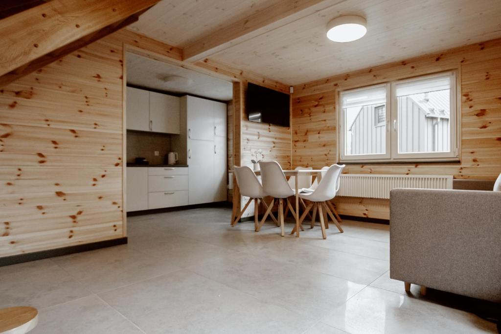 cocina con paredes de madera, mesa y sillas en Sudecki Domek, en Kudowa-Zdrój