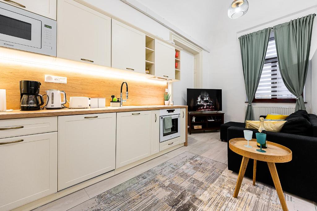 uma cozinha com armários brancos e uma sala de estar em Center Apartment Mlynska Kosice with private Parking em Košice