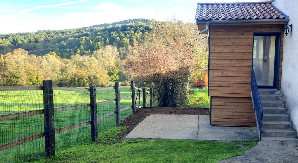 una pequeña casa con una valla al lado de un campo en Le Cocon Beaujolais, en Châtillon