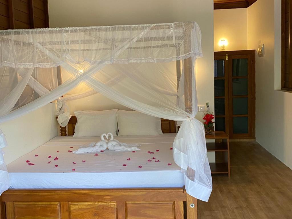 Un dormitorio con una cama con dosel con flores. en Hanguk Lanka Lagoon Villa en Tangalle