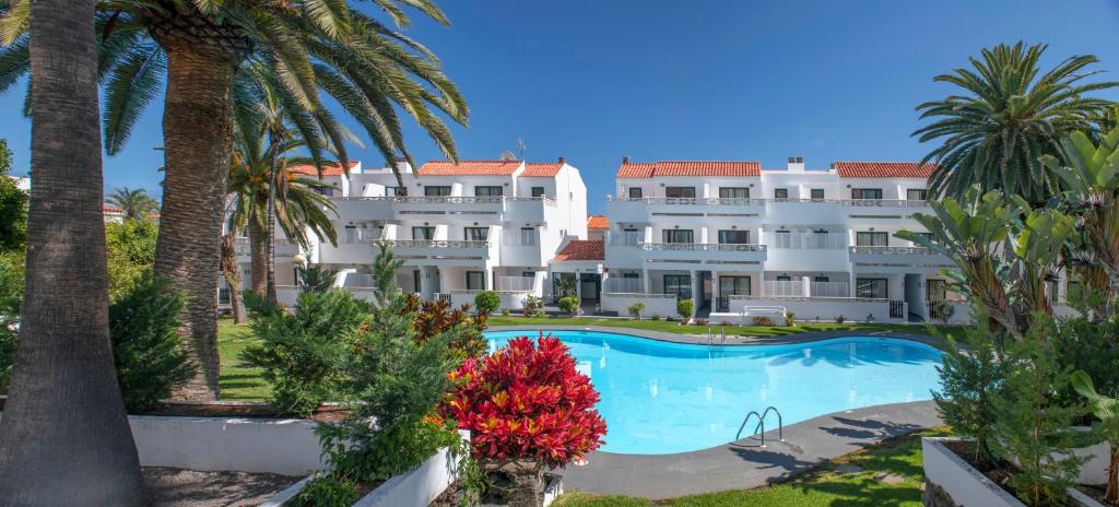 a large white building with a swimming pool and palm trees at Apartamentos Los Rosales in Los Cancajos