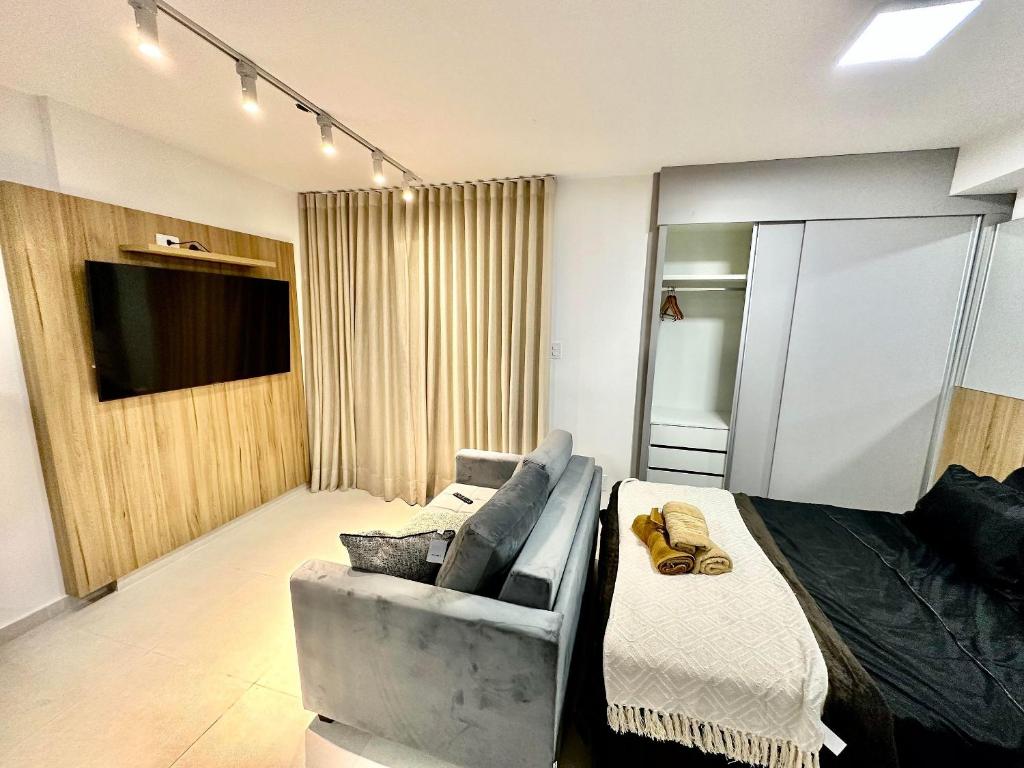 a room with a bed and a couch and a television at Stúdio Elegance Central - Av Itamar Franco in Juiz de Fora