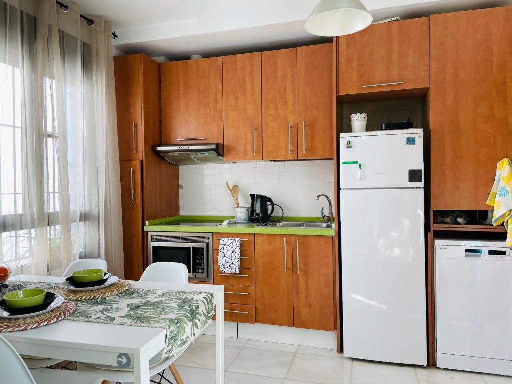 kuchnia z drewnianymi szafkami i białą lodówką w obiekcie Penthouse at City Center with Terrace w Sewilli