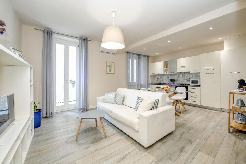 salon z białą kanapą i kuchnią w obiekcie Stella House w mieście Desenzano del Garda