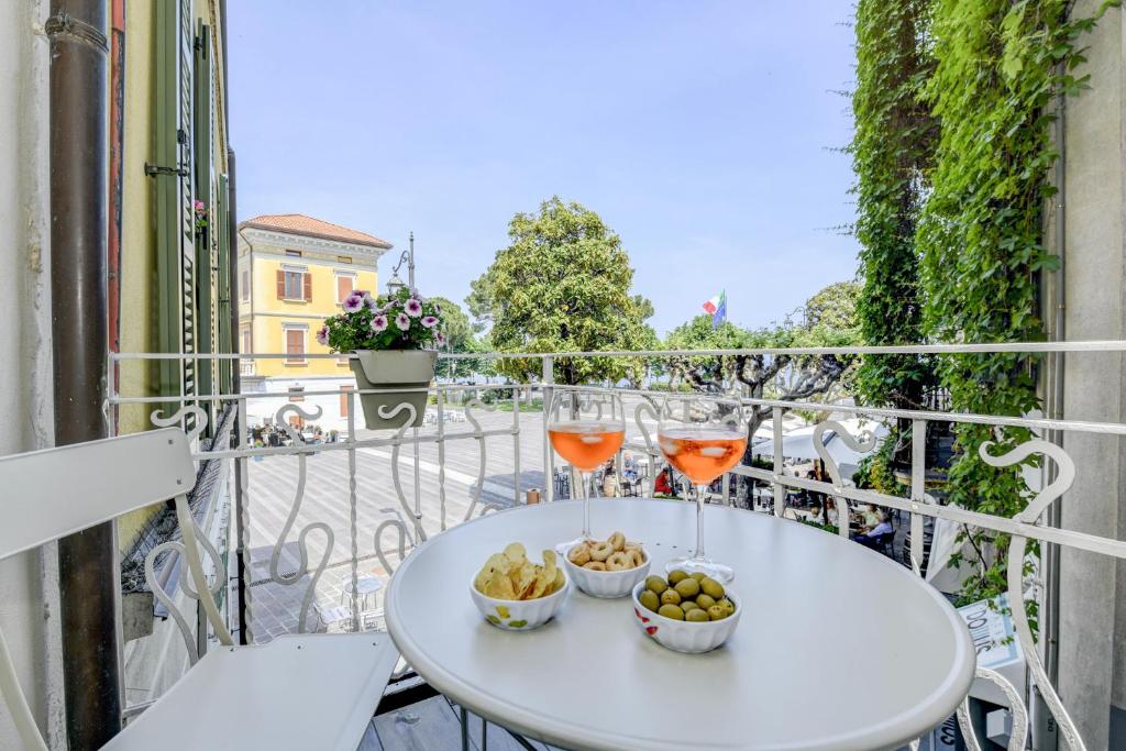 einen weißen Tisch mit Getränken und Schüsseln aus Essen auf dem Balkon in der Unterkunft Stella House in Desenzano del Garda