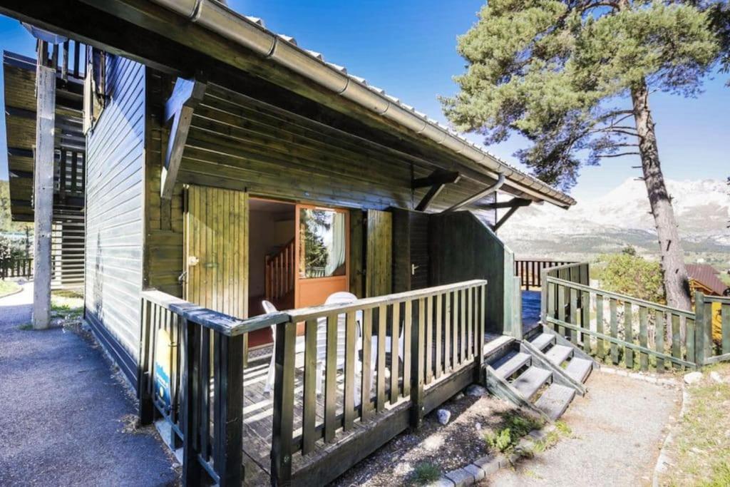 ein Holzhaus mit einer Veranda und einem Balkon in der Unterkunft Appartement duplex au pied des pistes in Le Dévoluy