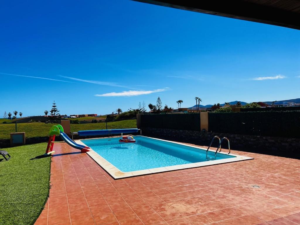 a swimming pool with a water slide in a yard at Villa Irina in Caleta De Fuste