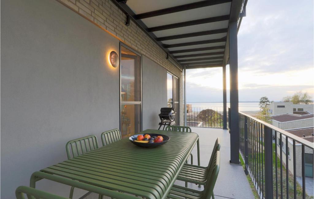 - une table verte avec un bol de fruits sur le balcon dans l'établissement 2 Bedroom Beach Front Apartment In Lembruch-dmmer See, à Lembruch