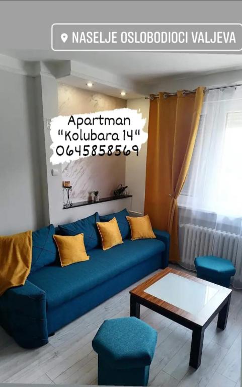 a living room with a blue couch and a table at Apartman Kolubara 14 in Valjevo