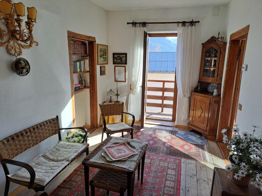 sala de estar con sofá, sillas y ventana en L' antica Casa di Maria Lilia en Pieve di Cadore