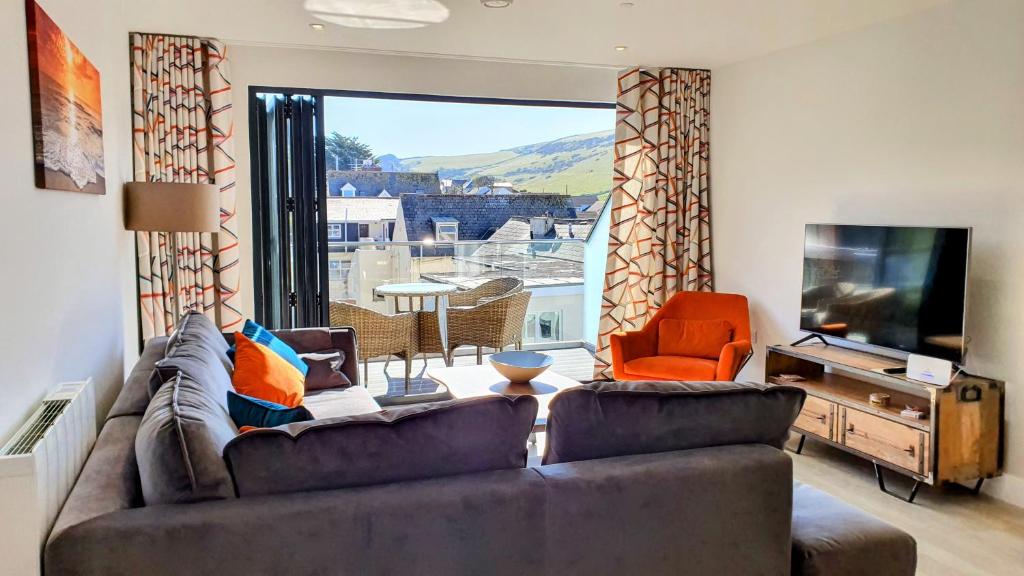 a living room with a couch and a television at 11 Putsborough - Luxury Apartment at Byron Woolacombe, only 4 minute walk to Woolacombe Beach! in Woolacombe