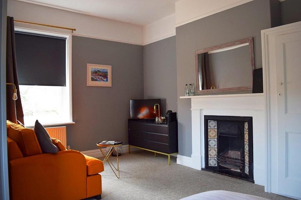 a living room with an orange couch and a fireplace at Blakeney House in Blakeney