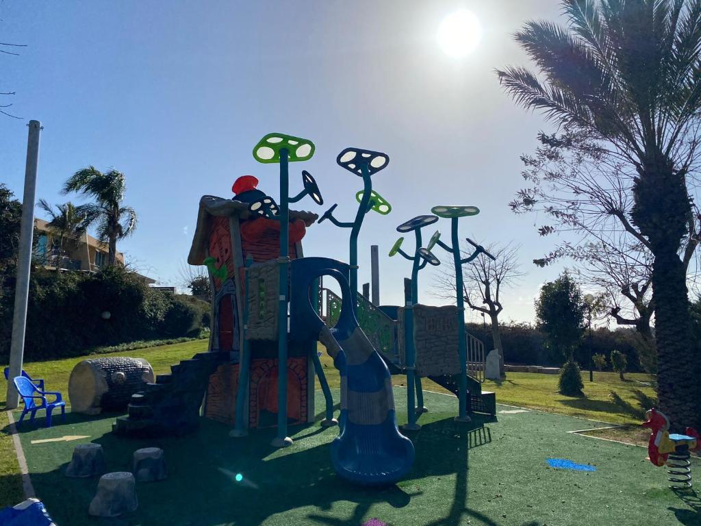 een speeltuin met een glijbaan in een park bij פרינסס סוויט קיסריה in Caesarea