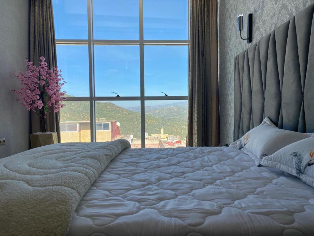 una camera da letto con un grande letto con una grande finestra di Hotel Golden Star a Taounate