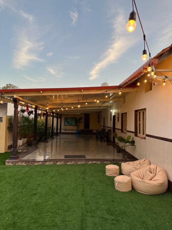 バンガロールにあるRustic Village Farmhouseの緑の芝生と照明のあるパティオ付きの家