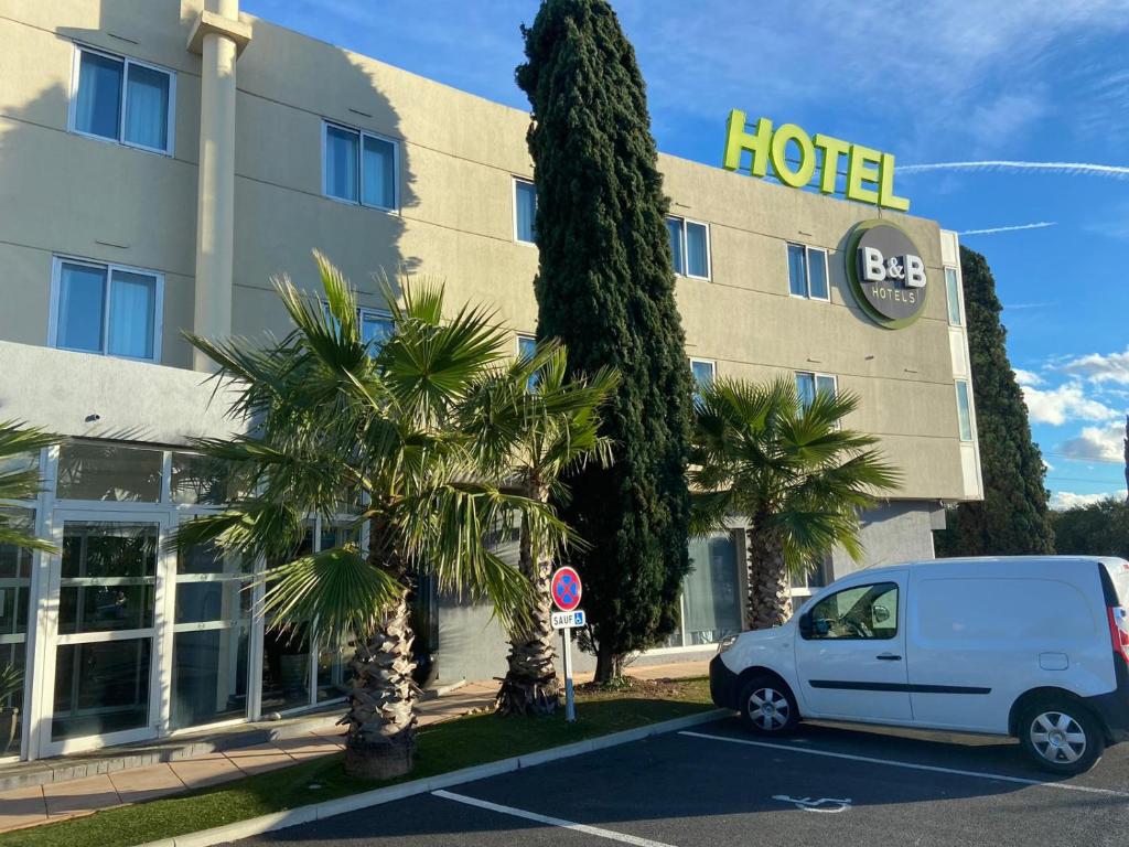 une voiture blanche garée devant un hôtel dans l'établissement B&B HOTEL Montpellier Vendargues, à Saint-Aunès