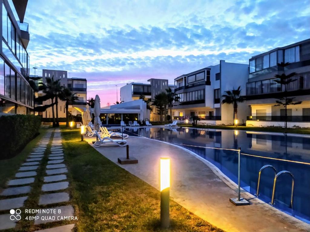 una piscina con luz junto a algunos edificios en Grand Apartement a Blanca Beach Sidi Rehal, en Sidi Rahal