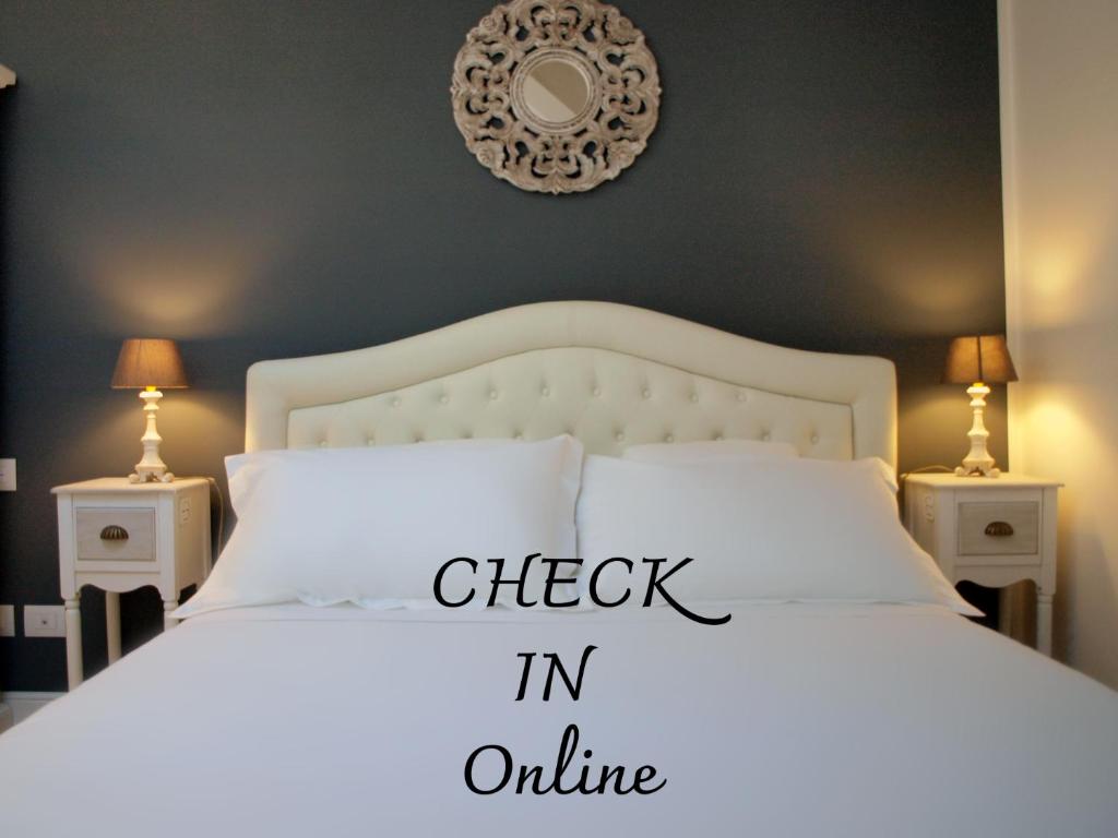 a white bed with a check in online sign on it at Acquaderni Rooms in Bologna