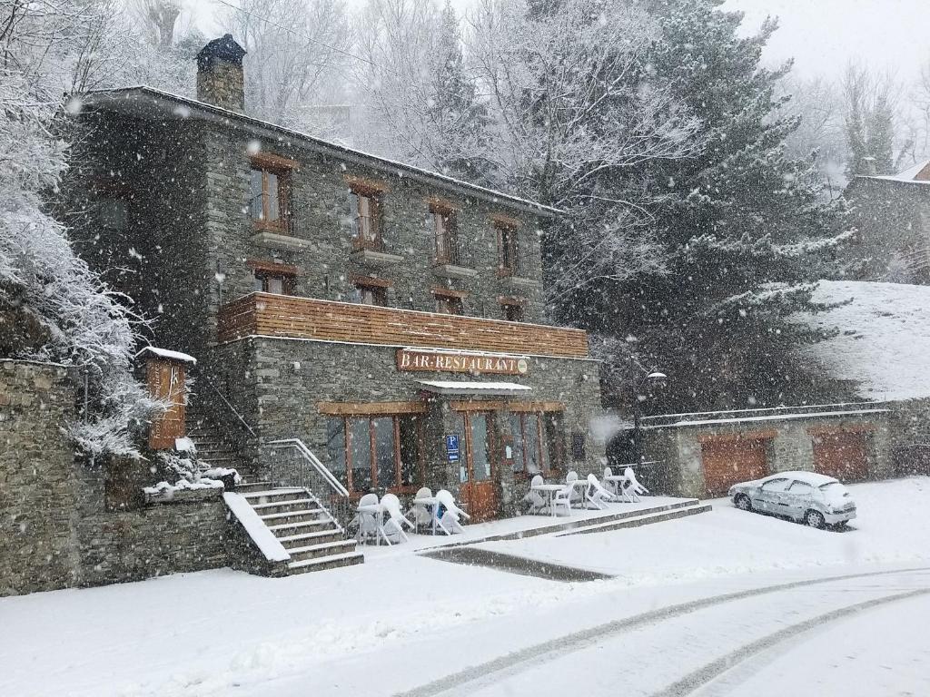 a building with people sitting outside in the snow at Hostal Les Roquetes in Queralbs