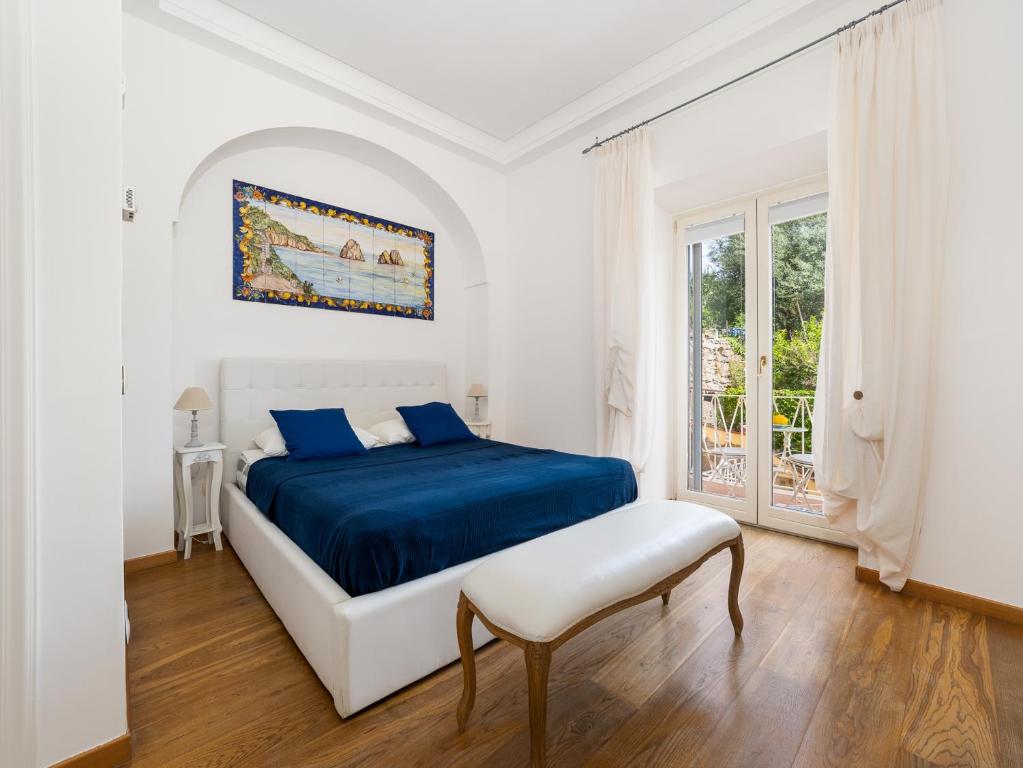 Un dormitorio blanco con una cama azul y una ventana en Villa Faraglioni 3 Bedrooms with Seaview en Sorrento