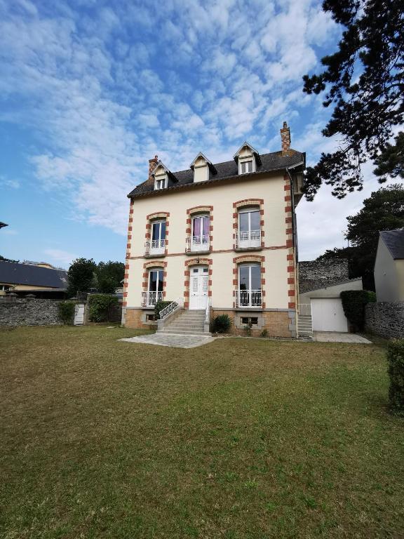 une grande maison avec une cour en gazon devant elle dans l'établissement Villa Jeanne Marie, à Saint-Pair-sur-Mer