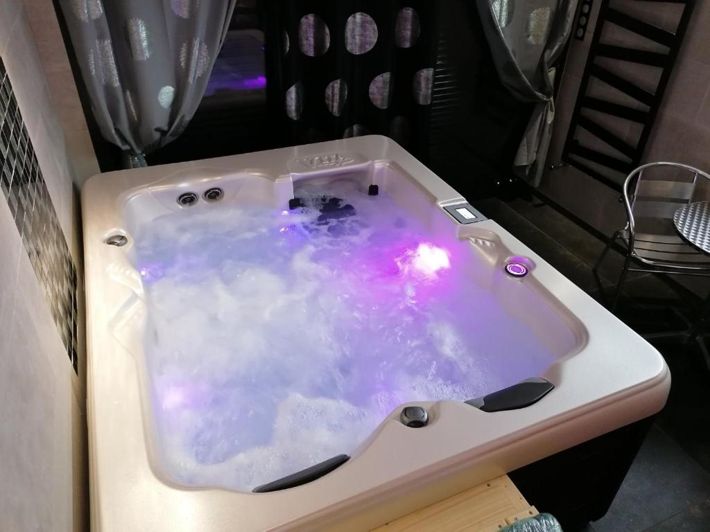 a white bath tub with a pink and purple substance at Chambre avec Spa et Sauna privatisés in Bourg-en-Bresse