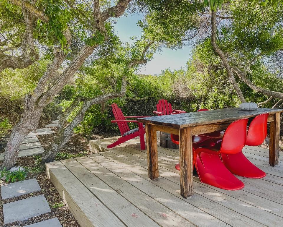 a wooden table and red chairs on a wooden deck at Rooisee in Yzerfontein