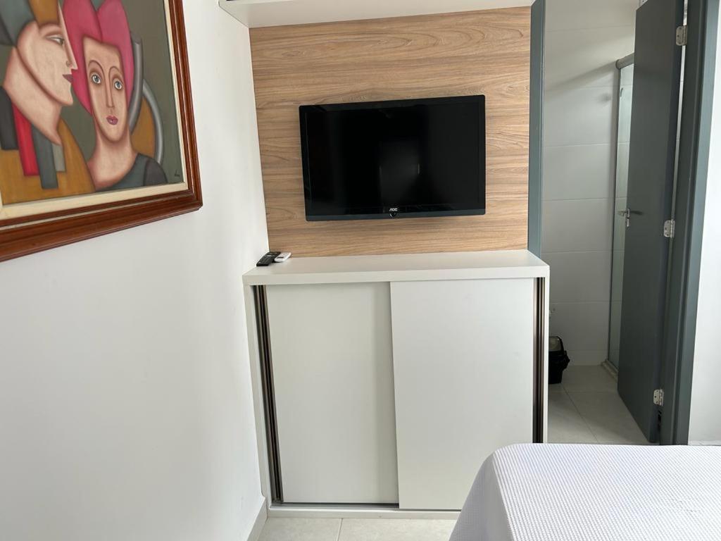 um quarto com uma televisão numa parede com um armário branco em Apartamento Intermares em Cabedelo