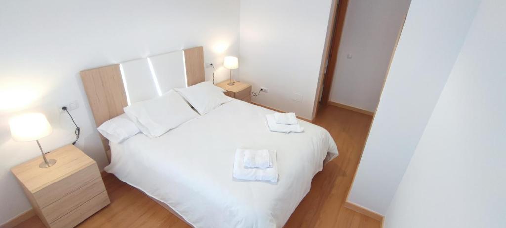 a bedroom with a white bed with two towels on it at Apartamentos Motilla del Azuer in Daimiel