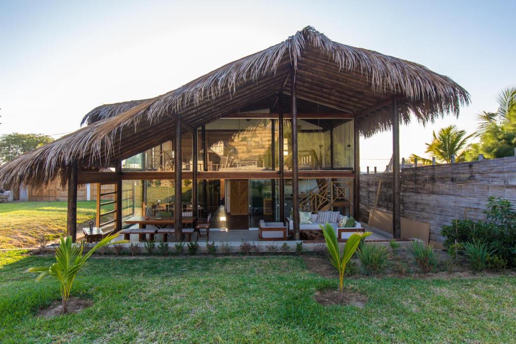 a house with a thatched roof in a yard at Zuzu Vichayito Casa para 9 con piscina in Los Órganos