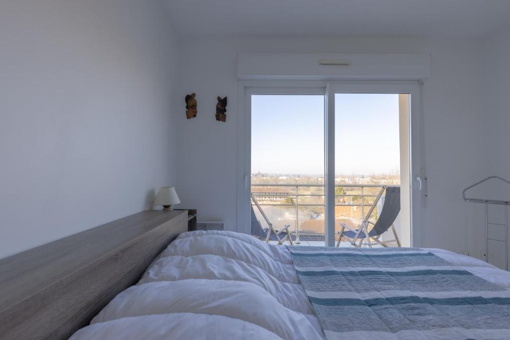 a bedroom with a large bed and a large window at LaConciergerieJonzac, Appartement La Désirade in Jonzac